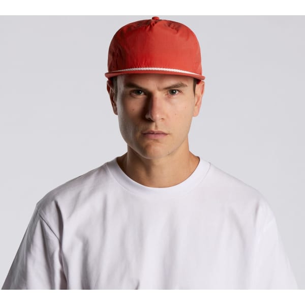A red cap with a flat brim is worn by a model in a plain white T-shirt. The cap features a logo on the front.
