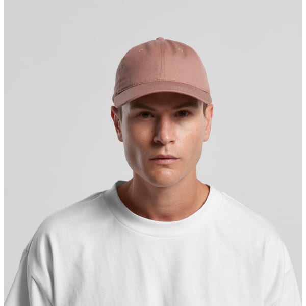 A cap in a soft pink shade, featuring a curved brim and an adjustable back, worn by a model in a white top.