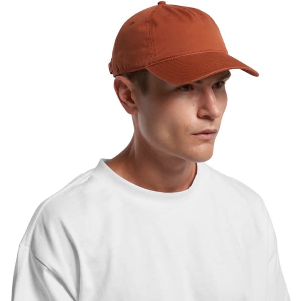 A five-panel cap in a rust colour worn by a model, featuring a logo on the front.