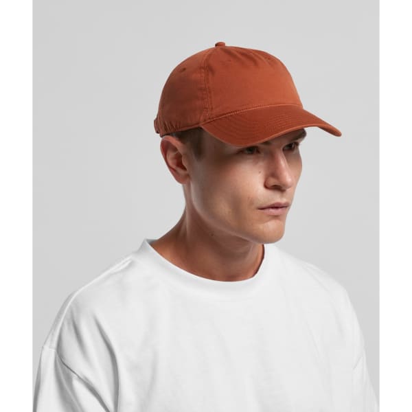 A brown five-panel cap worn by a person, featuring a rounded brim and a logo on the side.