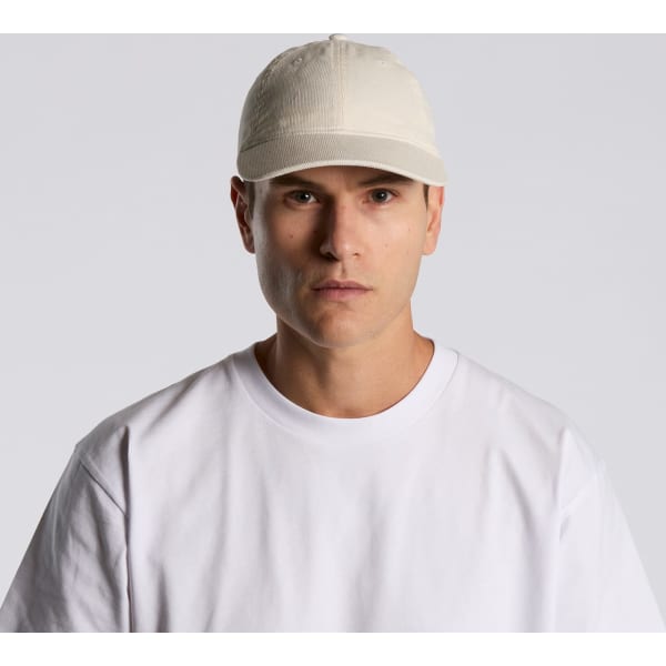 A beige cap worn by a model, featuring a front-panel design and a logo. The model is dressed in a white T-shirt.