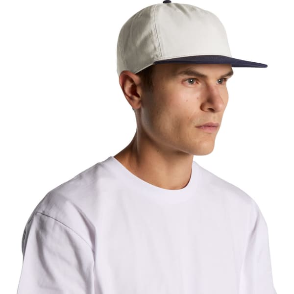 A two-tone cap featuring a white crown and a navy peak, with a person wearing it. The cap has a logo.