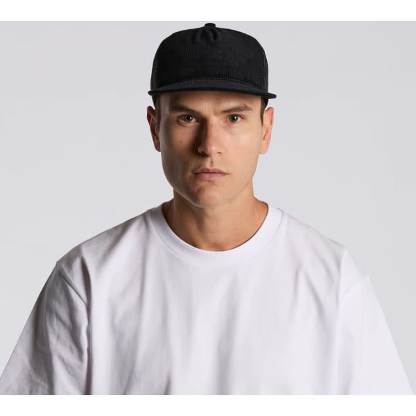 A black trucker cap featuring a mesh back, worn by a model dressed in a white T-shirt.