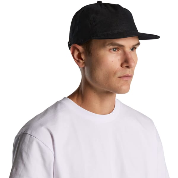 A black cap with a flat brim, featuring a logo on the front, displayed on a model wearing a white shirt.