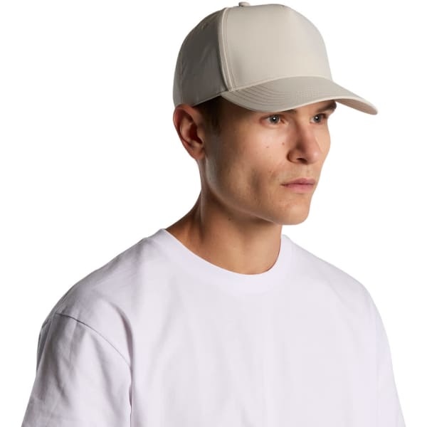 A beige nylon cap on a model, featuring a structured design and a logo.