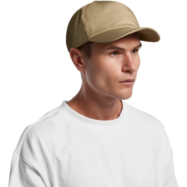 A beige soft cap worn by a person against a plain background. The cap features a logo.