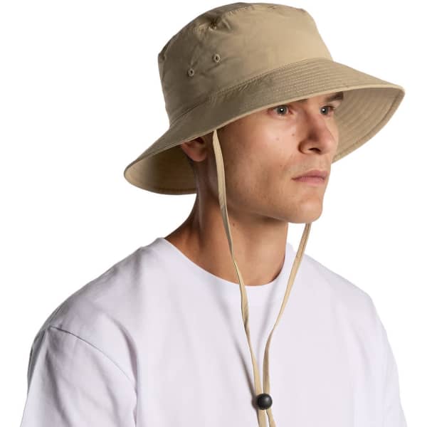 A beige nylon wide brim bucket hat with a chin strap, featuring ventilation eyelets and a logo.