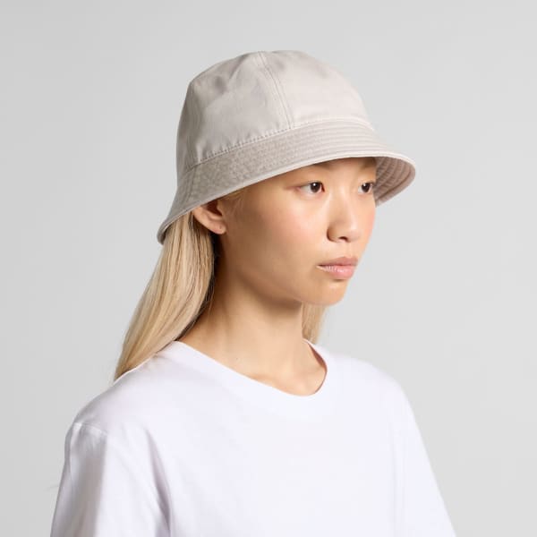 A cream-coloured bucket hat with a wide brim, featuring a stitched design and a subtle logo.