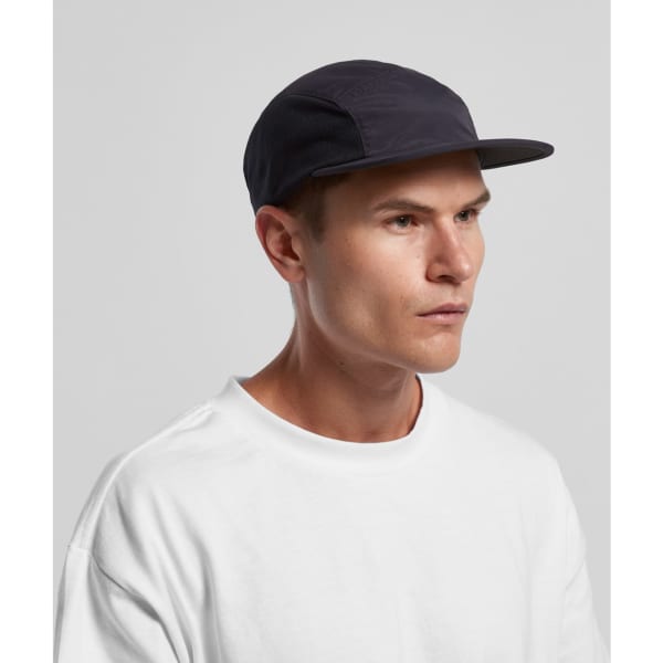 A dark cap with a flat brim and breathable mesh panels worn by a model in a white t-shirt.