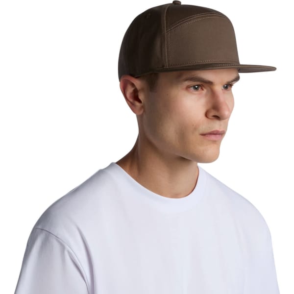 A brown 7-panel cap with a flat brim, featuring a logo, worn by a model in a white T-shirt.