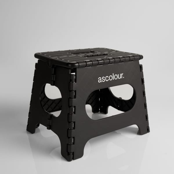 A black ASC Utility Stool with a textured surface and cut-out handles, featuring a logo. Ideal for leisure use.