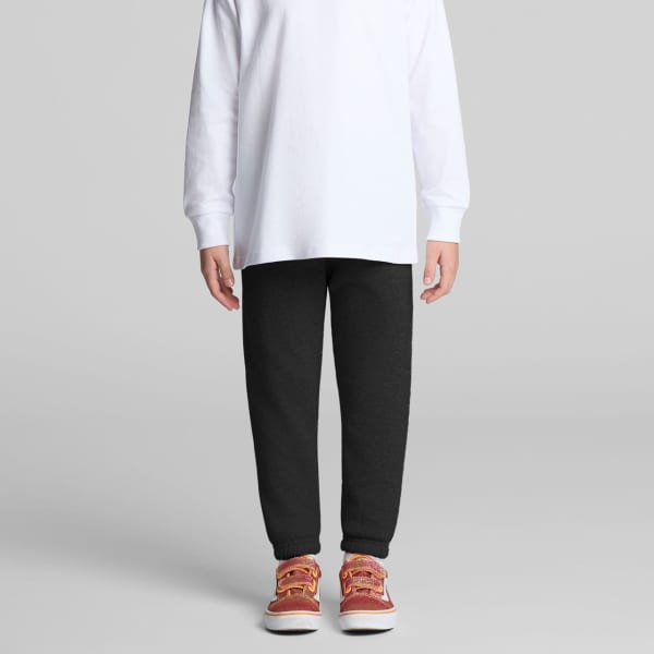 Track pants in dark grey, paired with a long-sleeve white top and red-orange shoes, featuring a logo.