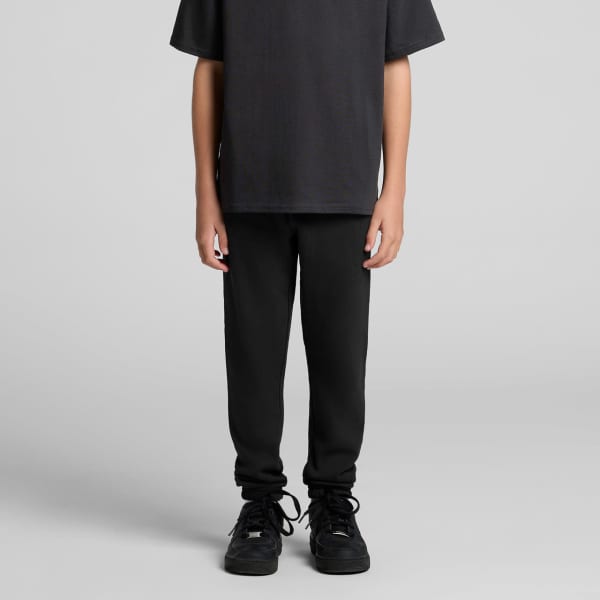 Youth track pants in black, featuring a relaxed fit and paired with a plain black t-shirt and shoes.