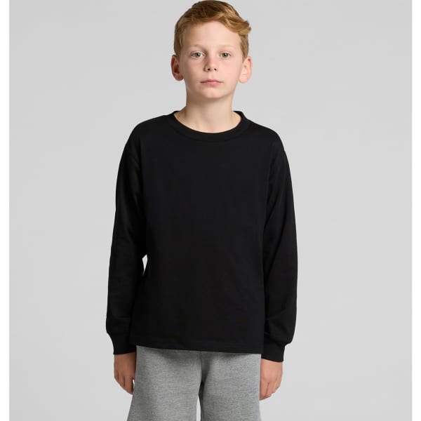A black long-sleeve t-shirt for youth modelled by a child, paired with grey pants. The shirt features a logo.