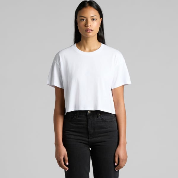 A white cropped t-shirt displayed on a model wearing black jeans, featuring a simple design and a logo.