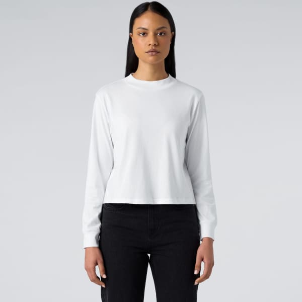 A white long sleeve tee, featuring a round neckline and a fitted design, worn with dark jeans.