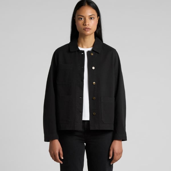 A black canvas chore jacket with a button front and pockets, worn by a model with long hair.