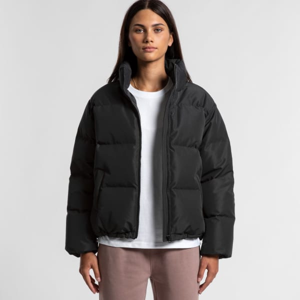 A black puffer jacket displayed on a model, featuring a high collar and a zip closure. The model wears a white top underneath.