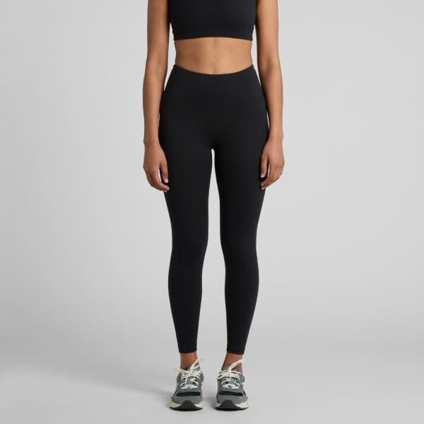 A pair of black seamless leggings displayed on a model, paired with a black crop top and running shoes.