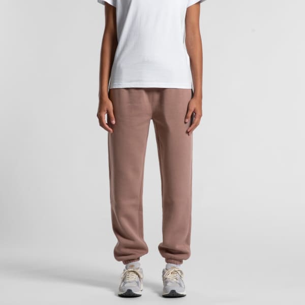 Relax Track Pants in soft taupe, featuring a casual fit and elasticated cuffs. Model paired with a white t-shirt and sneakers.