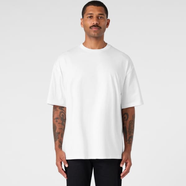 An oversized tee in white worn by a man with tattoos, featuring a simple design and a logo.