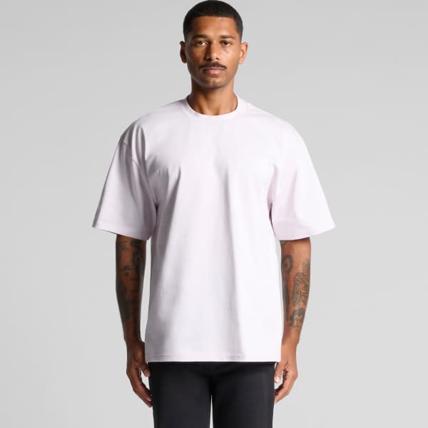 A light pink Heavy Tee featuring a relaxed fit and short sleeves, with a logo on the garment.
