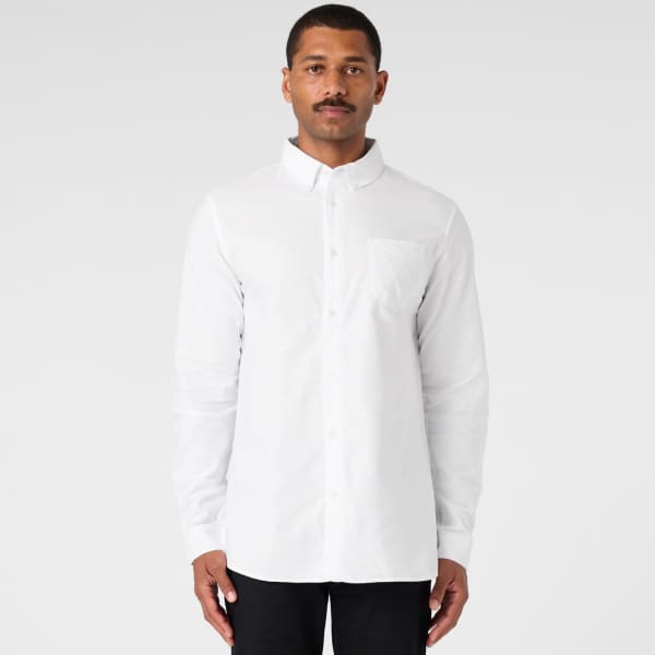 A white button-up Oxford shirt on a model, featuring a chest pocket and long sleeves. The shirt has a logo.