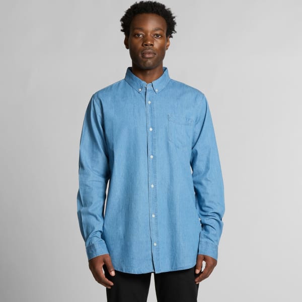 A blue denim shirt with a button-down collar and a pocket on the left side. The model stands against a plain background.