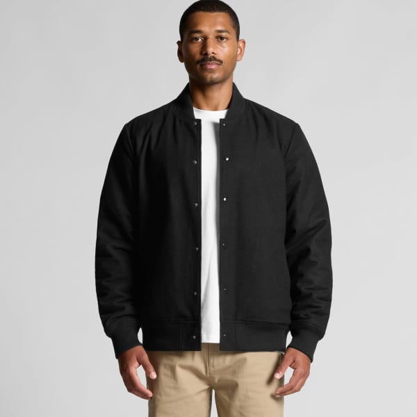 A man is wearing a black felt bomber jacket, featuring a front snap closure and ribbed cuffs.