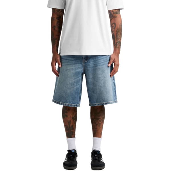 Denim shorts in light blue, featuring a relaxed fit and a stylish design, modelled on a person with tattoos.