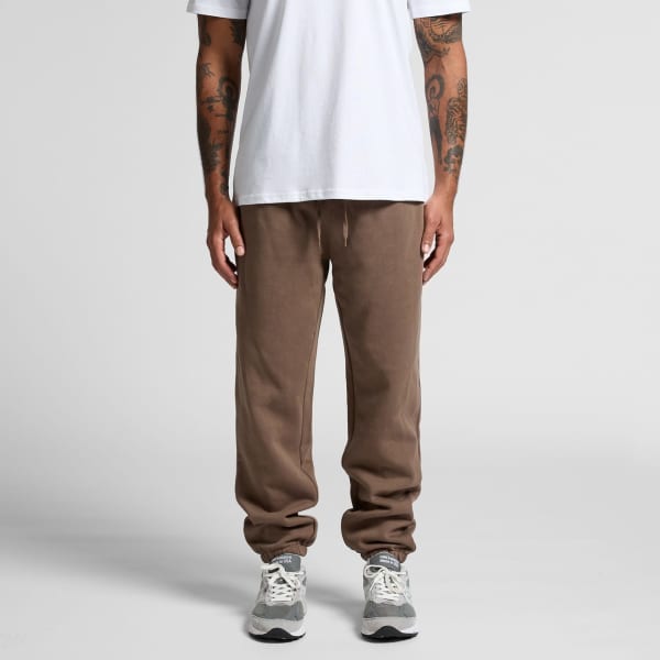 Brown track pants featuring a drawstring waist, styled with a plain white t-shirt and grey sneakers.