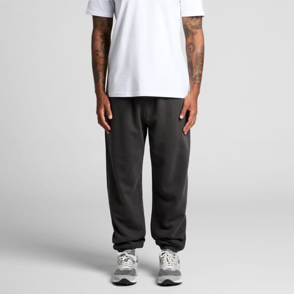 Faded black track pants with a relaxed fit, worn with a plain white t-shirt and grey sneakers.