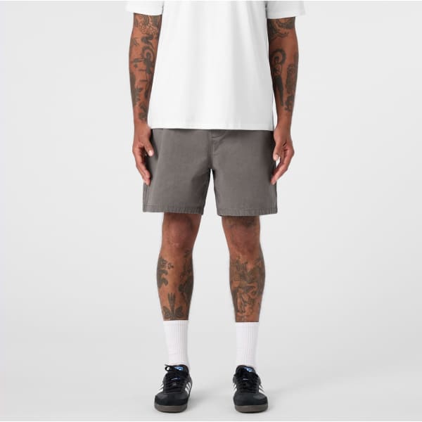 A pair of grey dress shorts featuring a simple design and a logo, modelled by a person with tattoos.