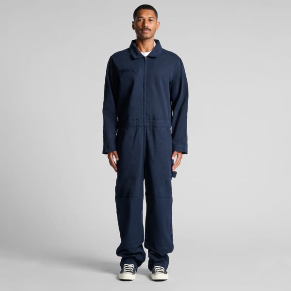 A man wearing navy blue canvas coveralls with a collar and pockets, standing in a neutral pose.