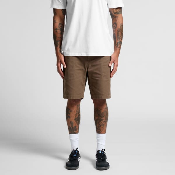 Canvas shorts in brown, featuring a casual design and pockets, displayed on a person with tattoos.