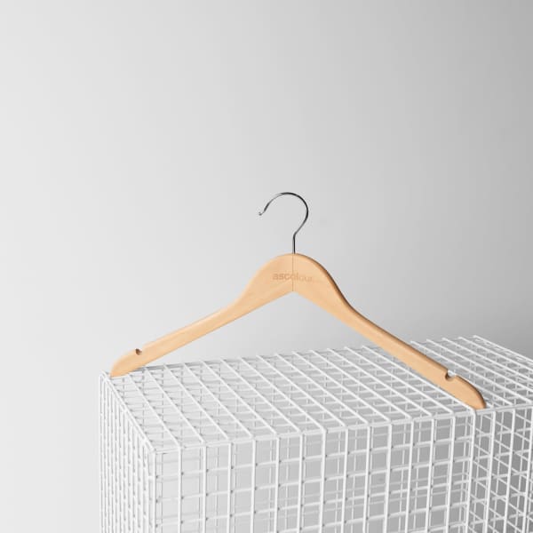 A wooden clothing hanger with a silver hook, featuring a logo, placed on a white wire grid.