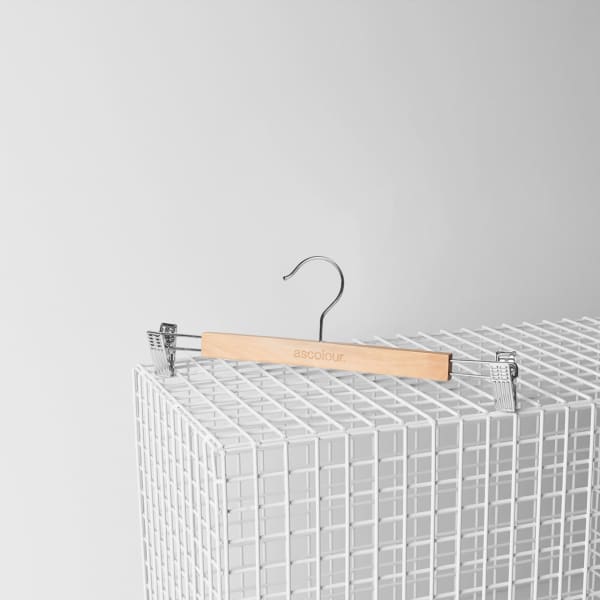 A wooden clip hanger with a silver hook, resting on a white wire display stand.