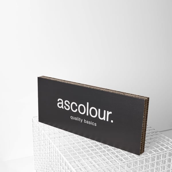A black branded plaque with a logo displayed on a white grid surface. The plaque features a simple, modern design.