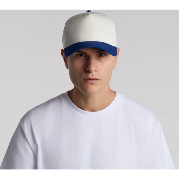 A two-tone cap featuring a cream front and blue peak, worn by a model in a white t-shirt.