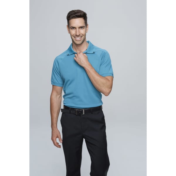 A man wearing a blue polo shirt with a collar, paired with black trousers, smiling confidently.