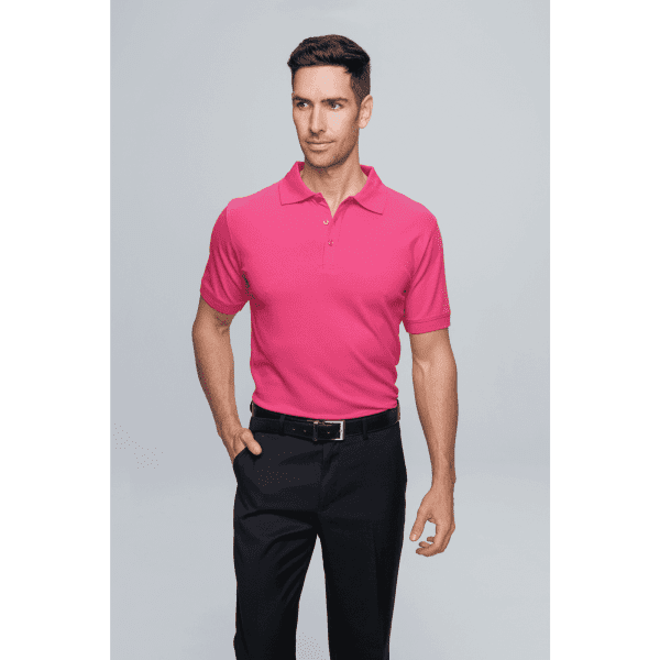 A man wearing a bright pink polo shirt and black trousers, standing confidently against a light background.
