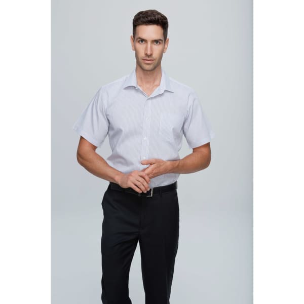 A short-sleeve button-up shirt in light grey, featuring a pocket and classic collar. The model is standing with arms crossed.