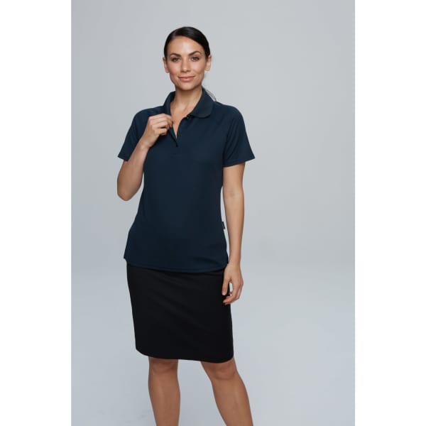 A woman models a navy blue polo shirt, paired with a black skirt, featuring a logo on the shirt.
