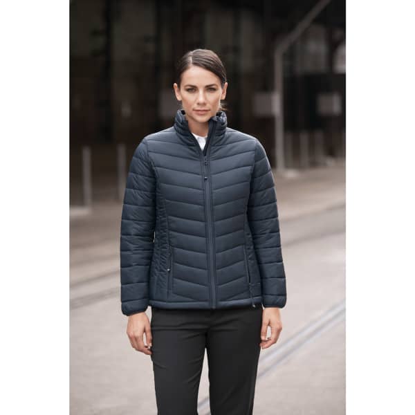 A navy puffer jacket with a zip front and a high collar, worn by a woman standing outdoors.