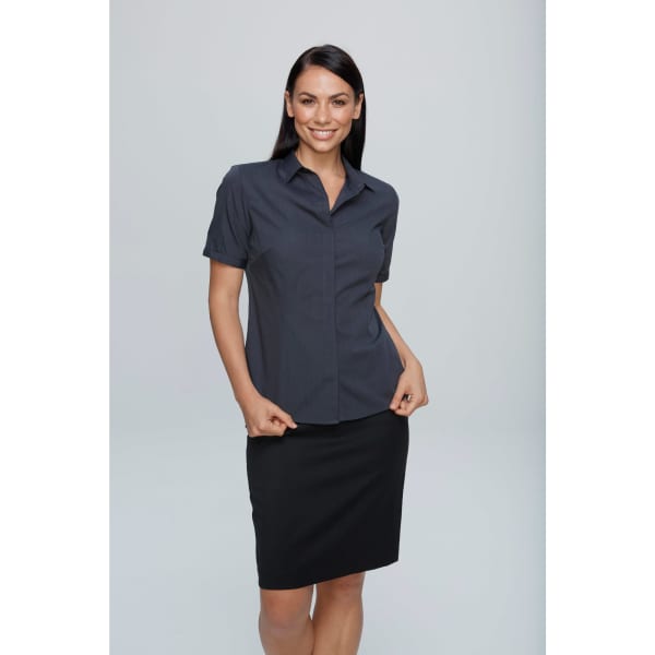 A woman wearing a short-sleeve button-up shirt in dark grey paired with a black pencil skirt. The shirt features a logo.