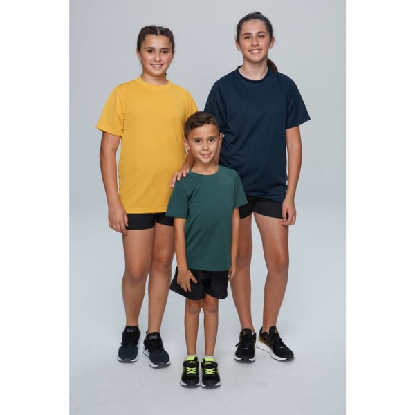 Three children, two girls in yellow and navy t-shirts, and a boy in a green t-shirt, all wearing shorts and sneakers.