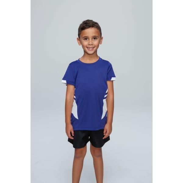 A smiling child wearing a blue T-shirt with white accents and black shorts, standing on a plain background.