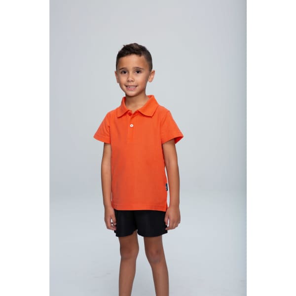 An orange polo shirt for kids, featuring a collar and a logo, worn by a smiling child against a plain background.