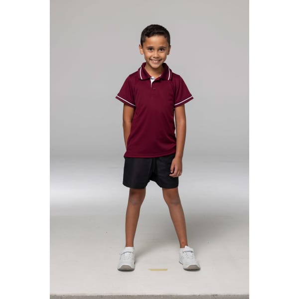A child wearing a maroon polo shirt with contrasting white stripes and black shorts, standing confidently.