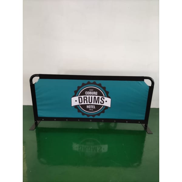 A freestanding café barrier with a teal fabric and a black frame featuring a logo in the centre.